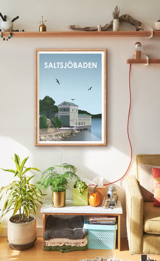 Ett vardagsrum med en tavla på väggen. Poster på Saltsjöbaden och dess gamla fina friluftsbad.