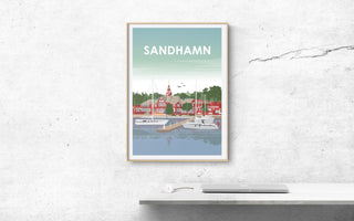 En poster över vackra Sandhamn. Segelbåtar ligger i hamnen och seglarhotellet i bakgrunden. Tavlan sitter på en vit putsad vägg